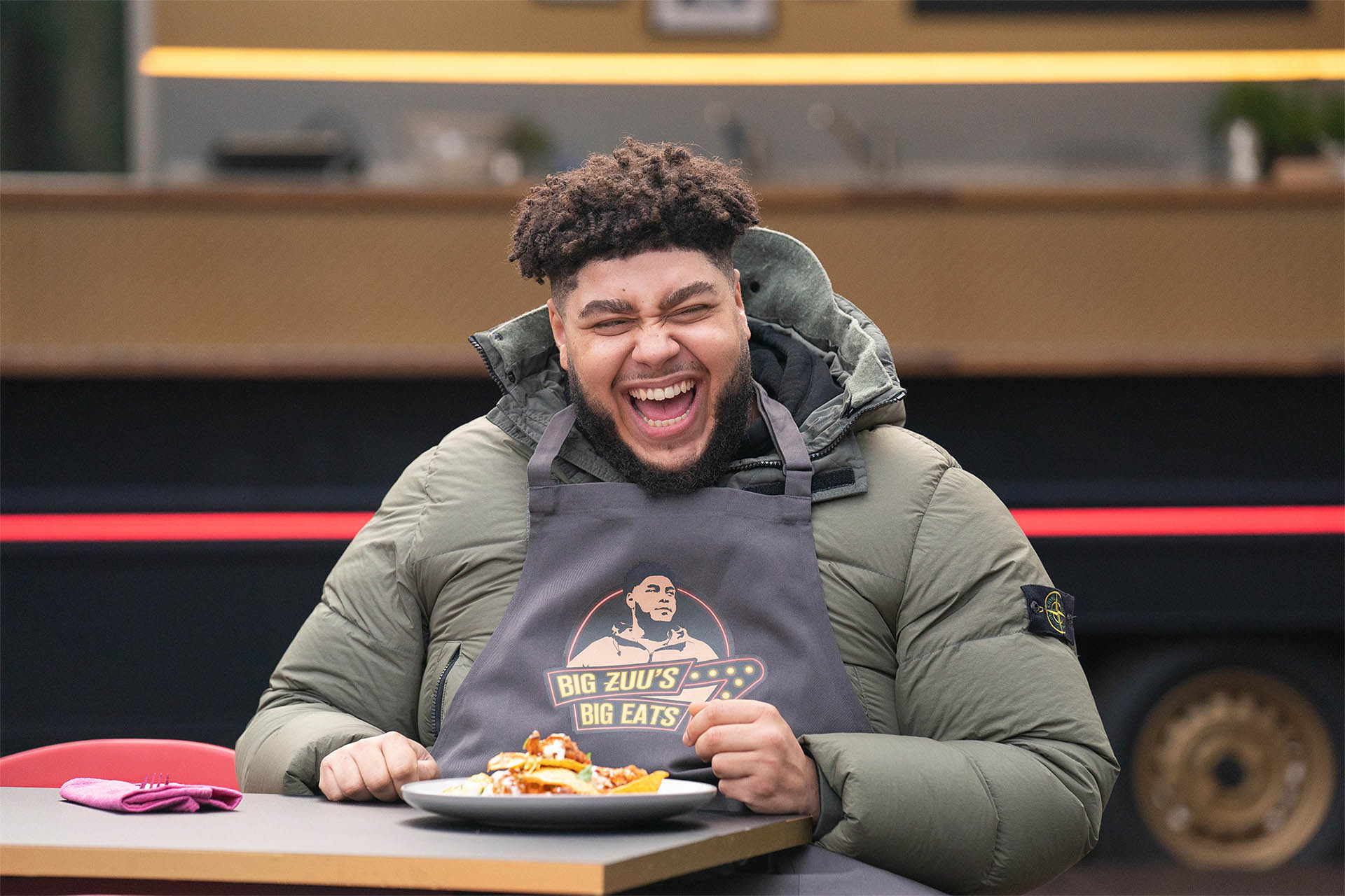 Big Zuu laughing outside his food truck while tucking into a plate of his food