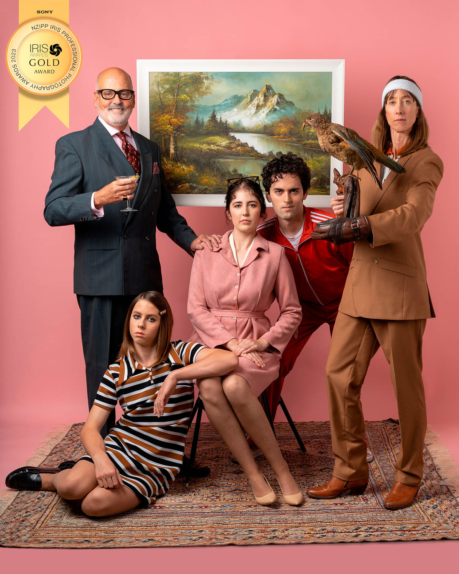 A five person family portrait, with everyone in costume. There is a pink backdrop and the photo has a gold award.